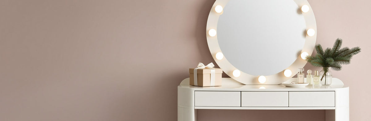Makeup vanity with a round lighted mirror against a blush pink wall